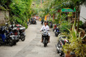 Ubud ist trotz zunehmendem Tourismus immer noch ein Ort mit kleinen Straßen, wenig Verkehr und vielen Zweirädern Strasse mit Roller in Ubud, Bali